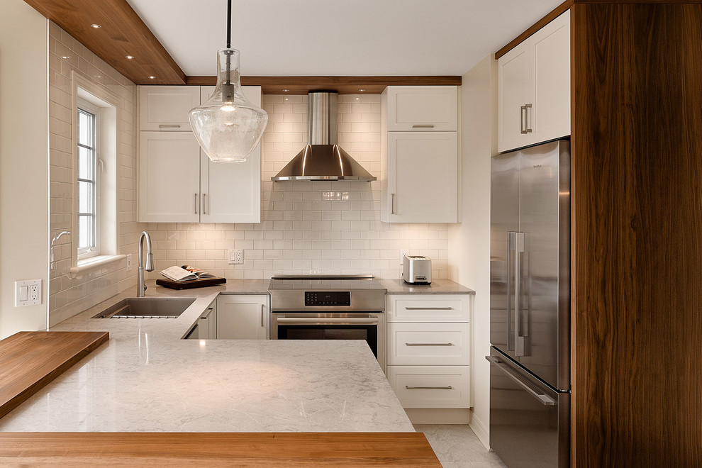Enclosed kitchen - contemporary l-shaped gray floor enclosed kitchen idea in Other with an undermount sink, shaker cabinets, white cabinets, white backsplash, stainless steel appliances, subway tile backsplash and a peninsula