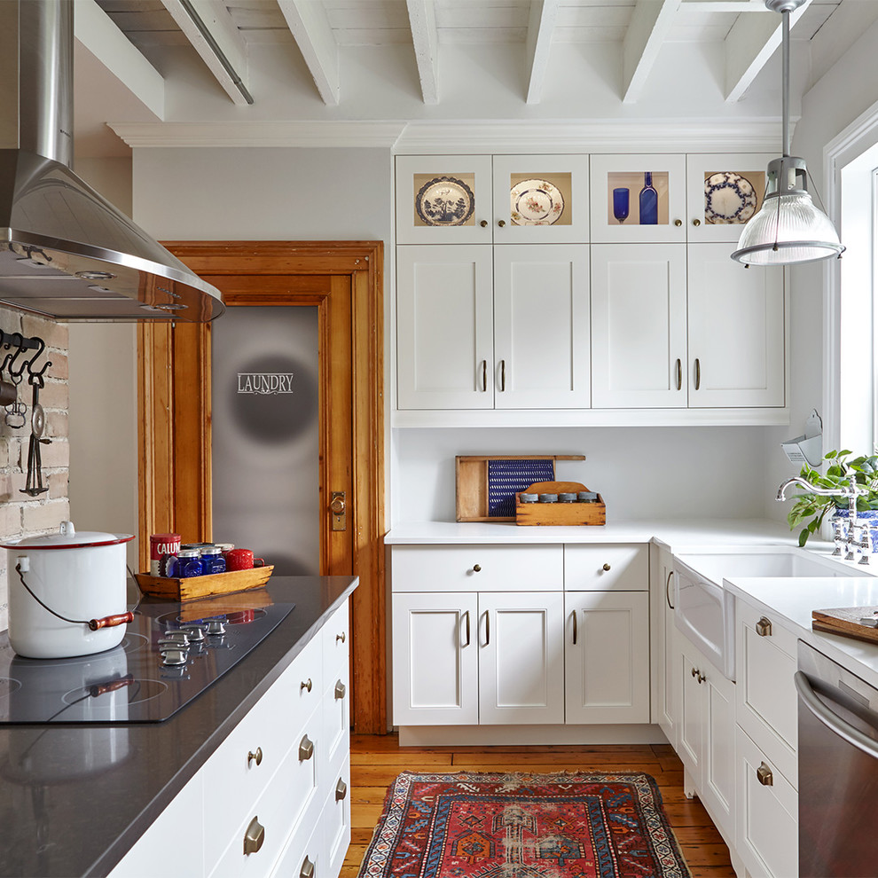 トロントにあるカントリー風のおしゃれなL型キッチン (エプロンフロントシンク、シェーカースタイル扉のキャビネット、白いキャビネット、無垢フローリング、シルバーの調理設備、茶色い床) の写真