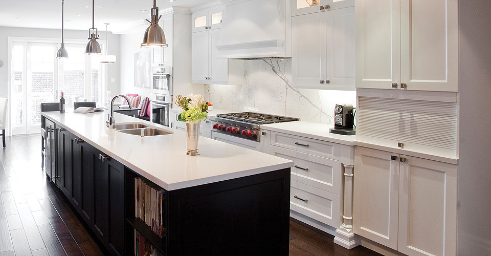 Modelo de cocina comedor lineal con armarios estilo shaker, puertas de armario blancas, salpicadero blanco, electrodomésticos de acero inoxidable y una isla