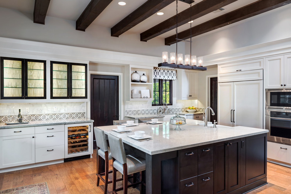 Example of a large transitional l-shaped light wood floor and brown floor kitchen design in Phoenix with a farmhouse sink, shaker cabinets, white cabinets, granite countertops, white backsplash, porcelain backsplash, stainless steel appliances and an island