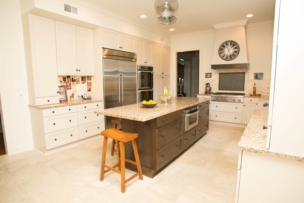 Photo of a medium sized traditional u-shaped kitchen in New Orleans with a submerged sink, recessed-panel cabinets, white cabinets, granite worktops, multi-coloured splashback, stone tiled splashback, stainless steel appliances, travertine flooring and an island.
