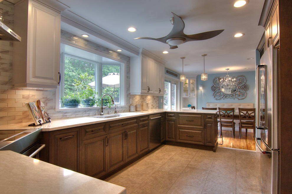 Mid-sized transitional u-shaped porcelain tile and beige floor eat-in kitchen photo in New York with an undermount sink, raised-panel cabinets, brown cabinets, quartz countertops, white backsplash, glass tile backsplash, stainless steel appliances, a peninsula and white countertops