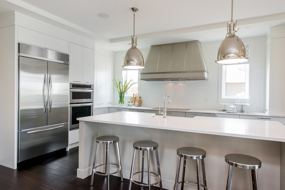 Inspiration for a large transitional l-shaped dark wood floor eat-in kitchen remodel in Calgary with a farmhouse sink, flat-panel cabinets, quartz countertops, white backsplash, subway tile backsplash, stainless steel appliances and an island