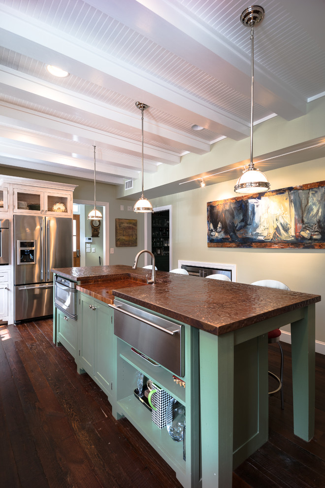 Klassisk inredning av ett avskilt, mellanstort u-kök, med en rustik diskho, luckor med infälld panel, vita skåp, bänkskiva i akrylsten, grönt stänkskydd, stänkskydd i keramik, rostfria vitvaror, mörkt trägolv och en köksö