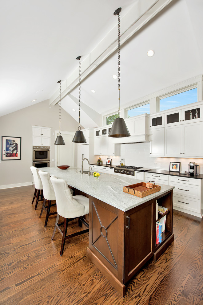 Foto på ett mellanstort vintage grå kök, med en undermonterad diskho, vita skåp, granitbänkskiva, vitt stänkskydd, en köksö, skåp i shakerstil, rostfria vitvaror, mellanmörkt trägolv och brunt golv