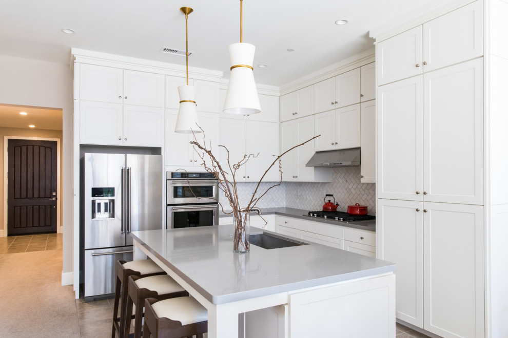 Example of a transitional l-shaped gray floor kitchen design in Denver with an undermount sink, shaker cabinets, white cabinets, white backsplash, stainless steel appliances, an island and gray countertops