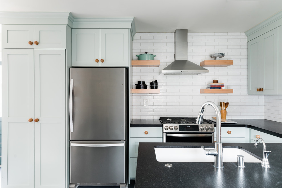 Idéer för att renovera ett mellanstort vintage svart svart kök, med en nedsänkt diskho, skåp i shakerstil, blå skåp, granitbänkskiva, vitt stänkskydd, stänkskydd i tegel, rostfria vitvaror, linoleumgolv, en halv köksö och blått golv