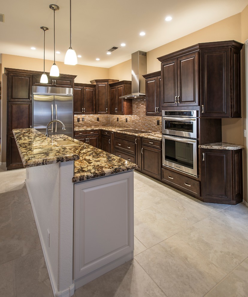 Open concept kitchen - mid-sized transitional l-shaped ceramic tile open concept kitchen idea in Phoenix with an undermount sink, raised-panel cabinets, dark wood cabinets, granite countertops, brown backsplash, glass tile backsplash, stainless steel appliances and an island
