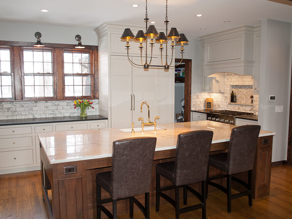 Example of a large transitional u-shaped medium tone wood floor eat-in kitchen design in Cleveland with a farmhouse sink, shaker cabinets, white cabinets, quartzite countertops, white backsplash, subway tile backsplash, stainless steel appliances and an island