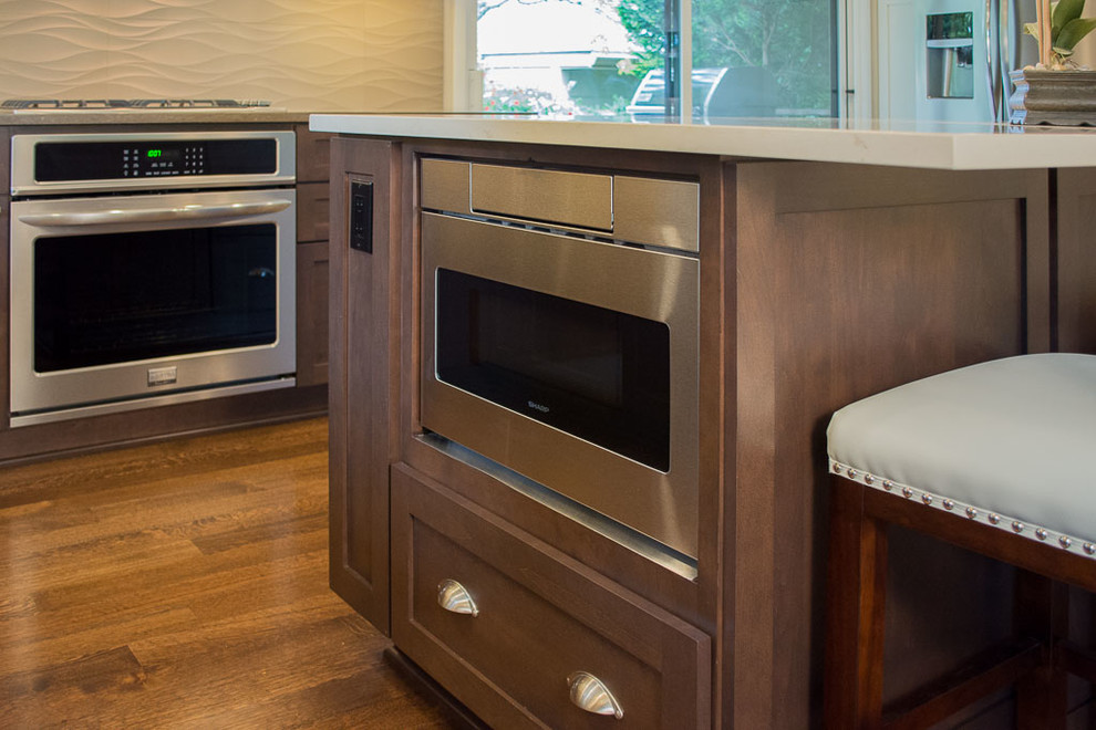 Réalisation d'une cuisine ouverte tradition en L et bois foncé de taille moyenne avec un évier encastré, un placard à porte shaker, un plan de travail en quartz modifié, une crédence beige, une crédence en carreau de porcelaine, un électroménager en acier inoxydable, parquet foncé et îlot.