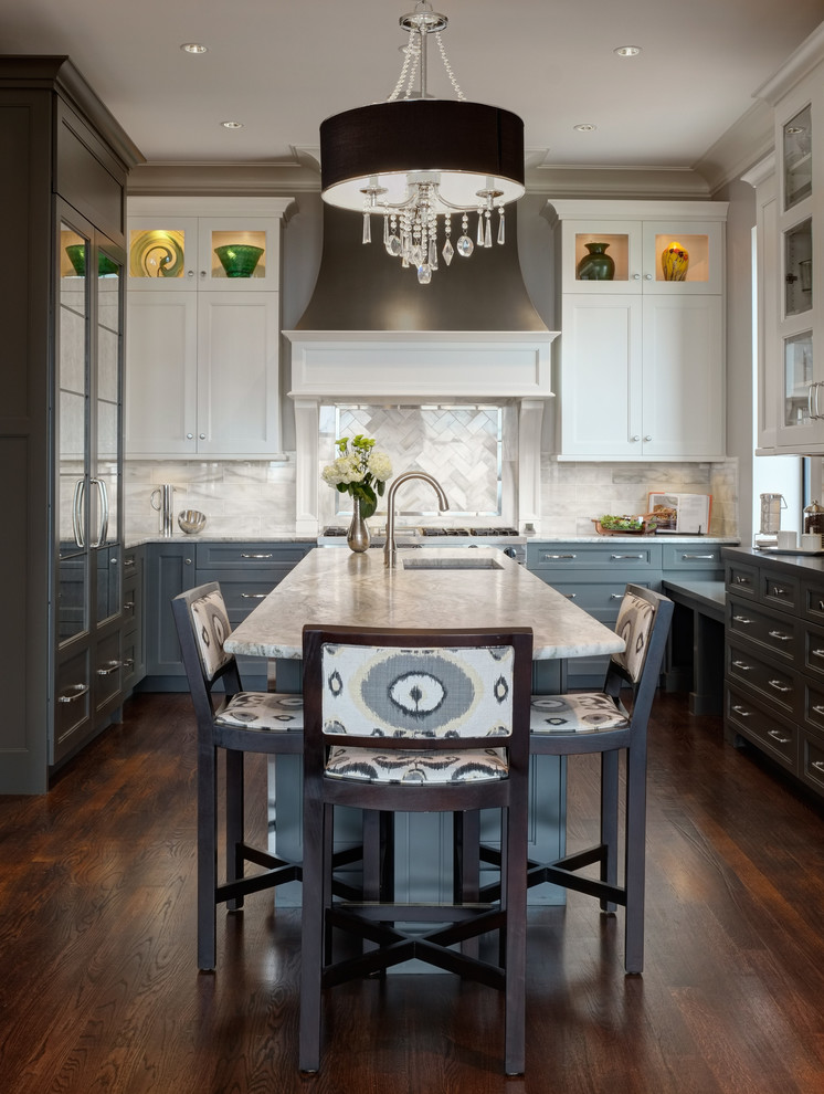 Aménagement d'une cuisine classique en U avec un placard avec porte à panneau encastré, des portes de placard grises, une crédence blanche, parquet foncé, îlot et un plan de travail en quartz.