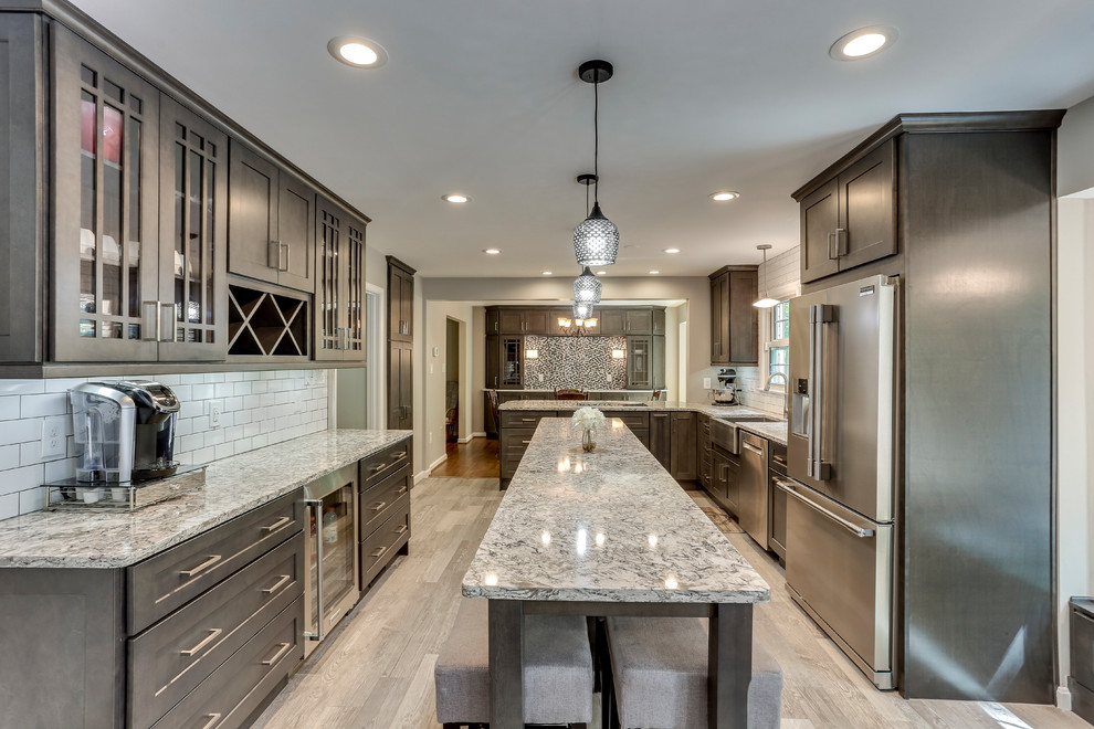 This is an example of a large traditional u-shaped kitchen in DC Metro with a belfast sink, shaker cabinets, grey cabinets, engineered stone countertops, white splashback, metro tiled splashback, stainless steel appliances and an island.
