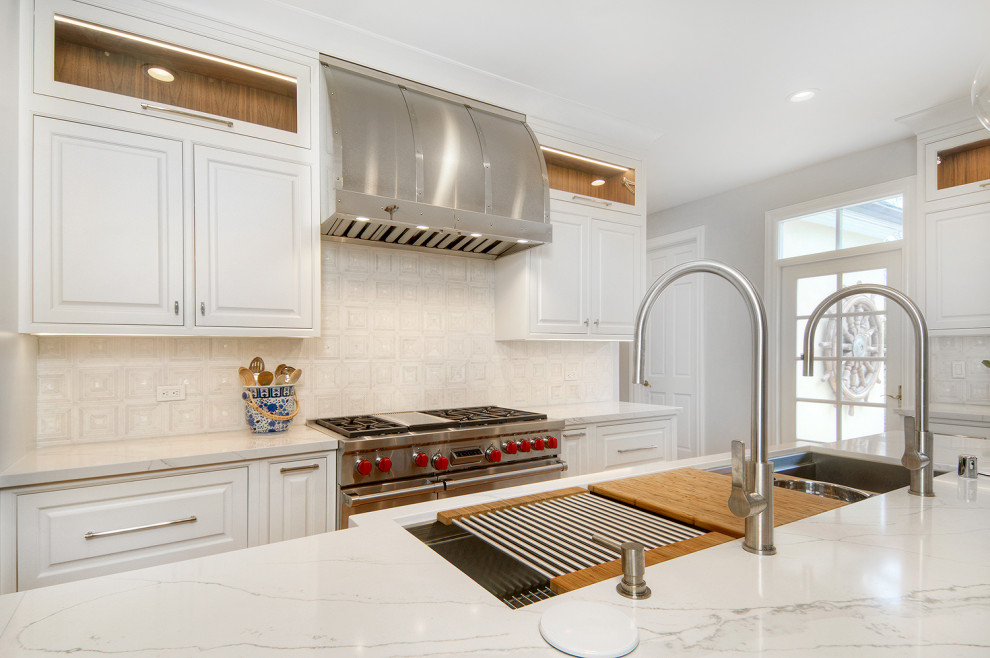 Exempel på ett stort klassiskt vit vitt kök, med en undermonterad diskho, luckor med profilerade fronter, vita skåp, bänkskiva i kvarts, vitt stänkskydd, stänkskydd i stenkakel, integrerade vitvaror, ljust trägolv, en köksö och beiget golv