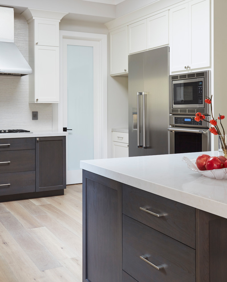Large transitional l-shaped gray floor eat-in kitchen photo in San Francisco with a single-bowl sink, shaker cabinets, white cabinets, white backsplash, stainless steel appliances, an island and white countertops