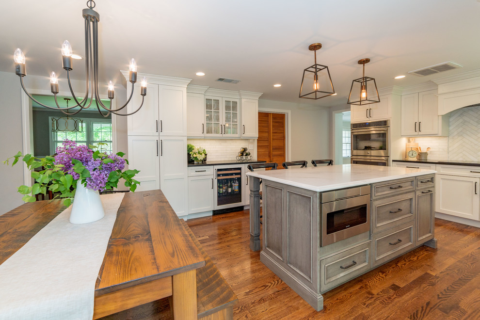 Large transitional u-shaped brown floor eat-in kitchen photo in Bridgeport with an undermount sink, shaker cabinets, white cabinets, granite countertops, white backsplash, stainless steel appliances, an island and multicolored countertops