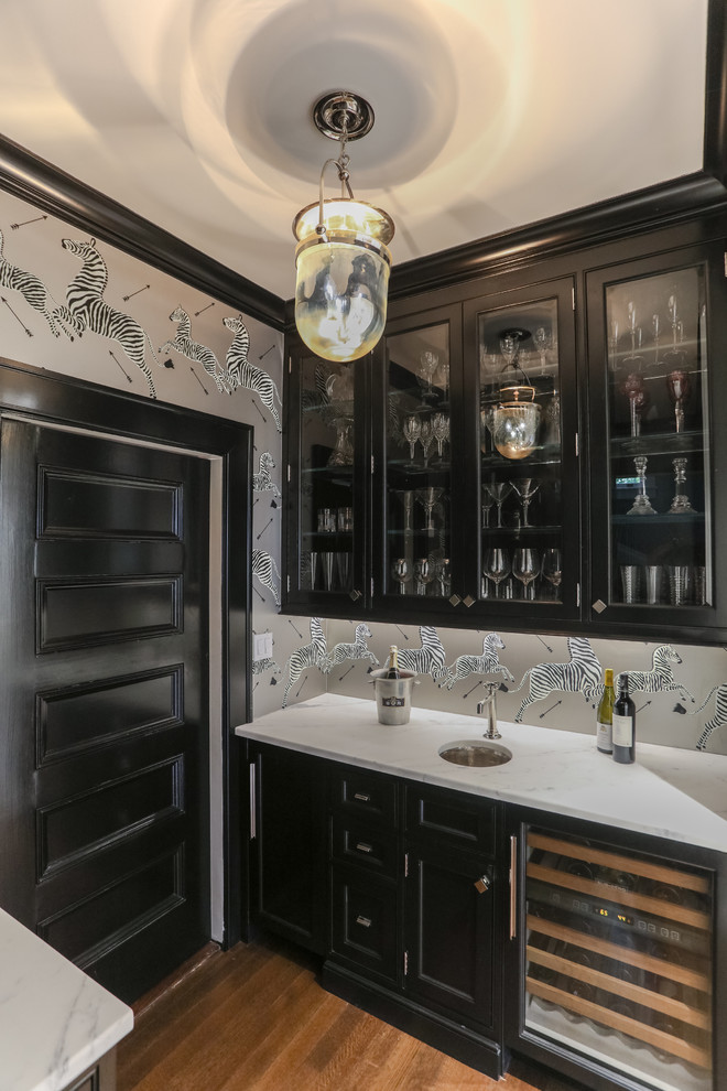 Idee per una cucina parallela tradizionale con lavello sottopiano, ante di vetro, ante nere, paraspruzzi grigio, pavimento in legno massello medio, pavimento marrone e top bianco