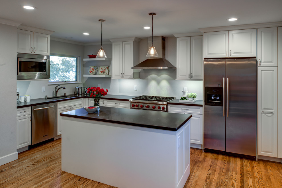 Exempel på ett mellanstort klassiskt kök, med en undermonterad diskho, luckor med upphöjd panel, vita skåp, bänkskiva i kvarts, rostfria vitvaror, en köksö och mellanmörkt trägolv