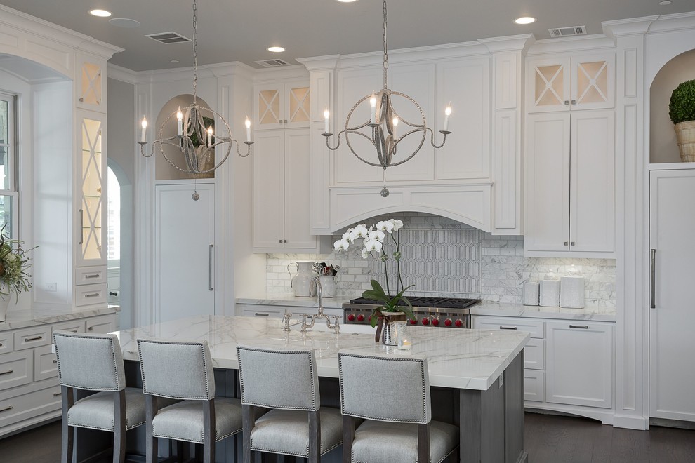 Design ideas for a large traditional l-shaped kitchen in Dallas with white cabinets, white splashback, dark hardwood flooring, an island, white worktops, a belfast sink, shaker cabinets, marble splashback, stainless steel appliances, brown floors and quartz worktops.