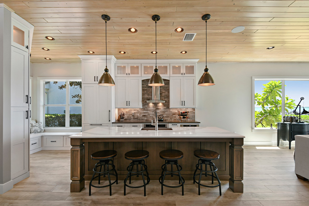 Eat-in kitchen - large transitional l-shaped light wood floor and beige floor eat-in kitchen idea in Orlando with an undermount sink, shaker cabinets, white cabinets, marble countertops, brown backsplash, stone tile backsplash, paneled appliances and an island