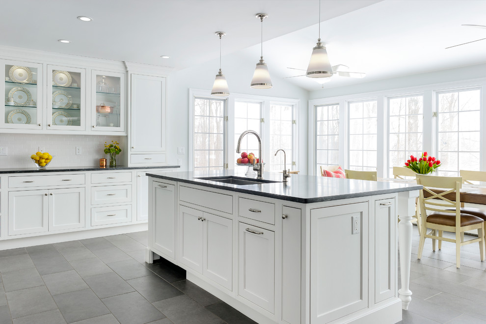This is an example of an expansive traditional u-shaped kitchen/diner in New York with a submerged sink, beaded cabinets, white cabinets, granite worktops, white splashback, metro tiled splashback, stainless steel appliances, porcelain flooring and an island.