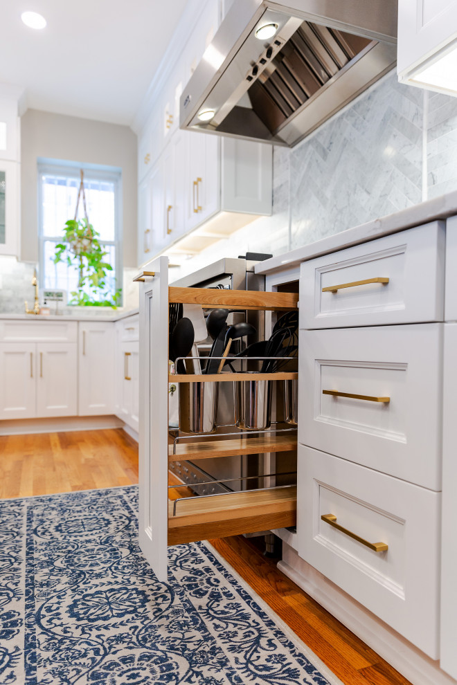 Foto på ett stort vintage vit kök, med en rustik diskho, luckor med infälld panel, vita skåp, bänkskiva i kvarts, grått stänkskydd, stänkskydd i marmor, rostfria vitvaror, mellanmörkt trägolv, en köksö och brunt golv