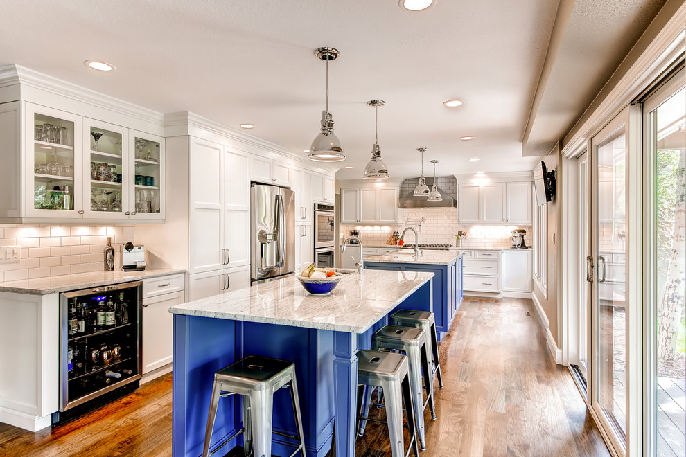 Inspiration for a large transitional single-wall medium tone wood floor and brown floor open concept kitchen remodel in Raleigh with recessed-panel cabinets, blue cabinets, white backsplash, stainless steel appliances, two islands, marble countertops and subway tile backsplash