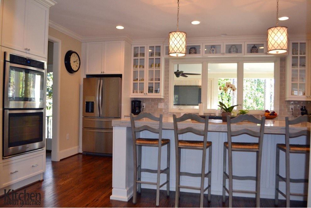 Bild på ett vintage kök och matrum, med en rustik diskho, skåp i shakerstil, vita skåp, grått stänkskydd, rostfria vitvaror, mellanmörkt trägolv och en köksö