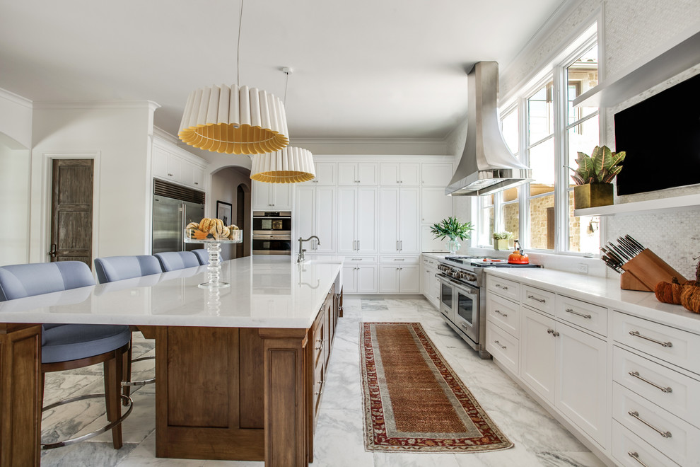 This is an example of an expansive traditional single-wall open plan kitchen in Dallas with a belfast sink, shaker cabinets, white cabinets, marble worktops, white splashback, mosaic tiled splashback, stainless steel appliances, marble flooring and an island.