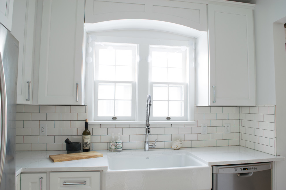 Design ideas for a small traditional kitchen/diner in Detroit with a belfast sink, shaker cabinets, white cabinets, engineered stone countertops, white splashback, ceramic splashback, stainless steel appliances and a breakfast bar.