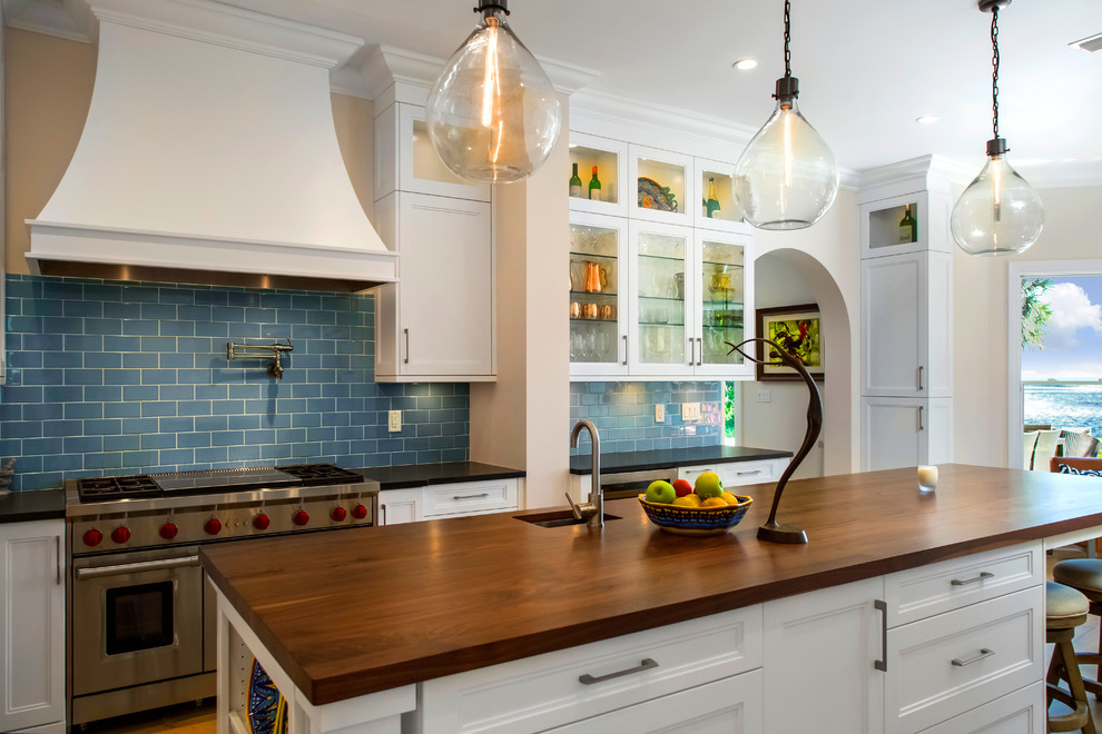 タンパにある高級な広いトランジショナルスタイルのおしゃれなキッチン (エプロンフロントシンク、シェーカースタイル扉のキャビネット、白いキャビネット、木材カウンター、青いキッチンパネル、サブウェイタイルのキッチンパネル、シルバーの調理設備、無垢フローリング、茶色い床、黒いキッチンカウンター) の写真