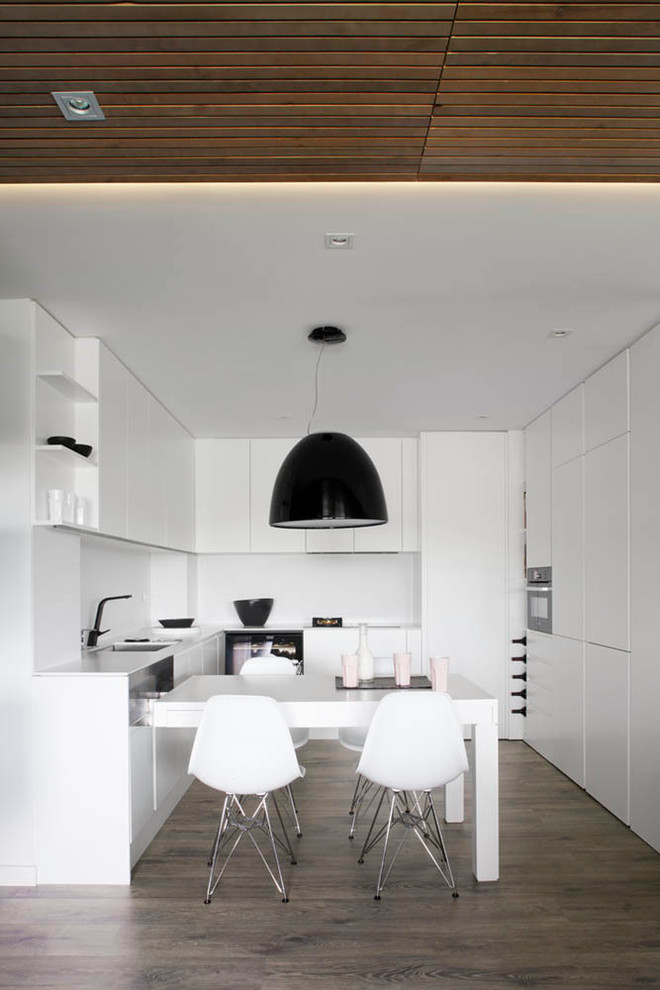 На фото: п-образная кухня в современном стиле с обеденным столом, плоскими фасадами, белым фартуком и черно-белыми фасадами с