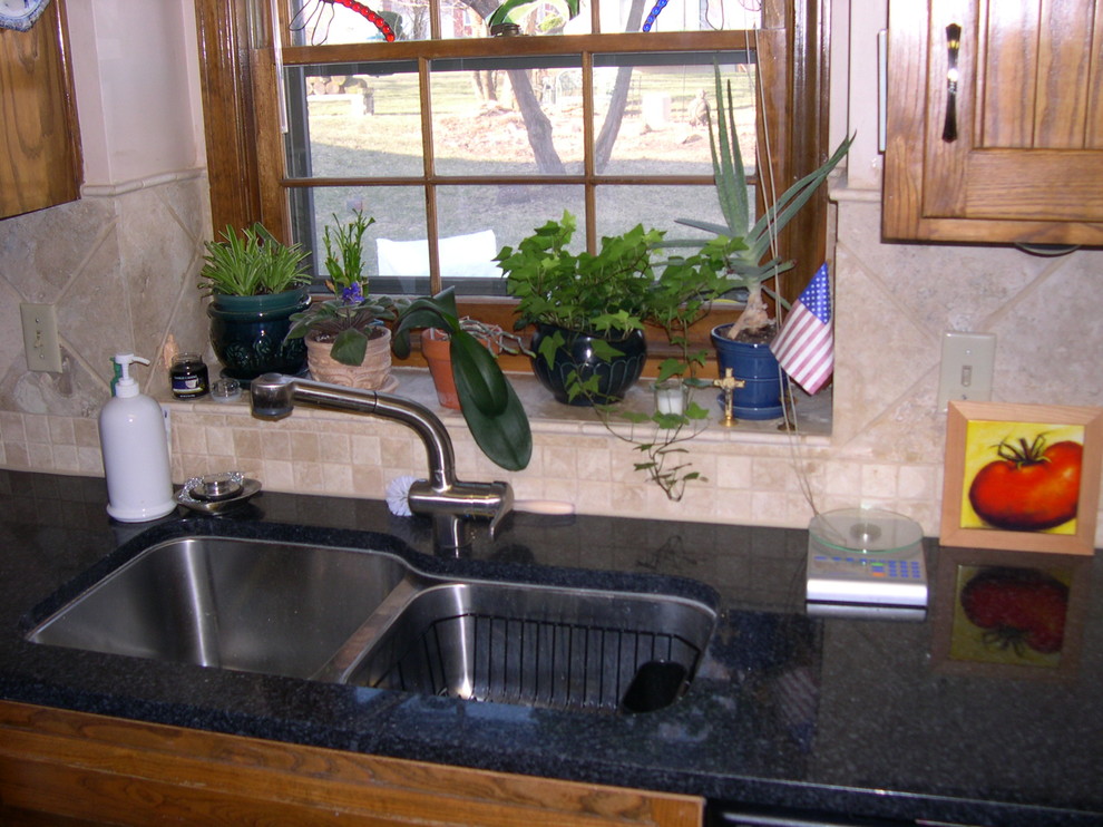Example of a small farmhouse l-shaped eat-in kitchen design in Kansas City with a double-bowl sink, brown backsplash, stone tile backsplash and an island