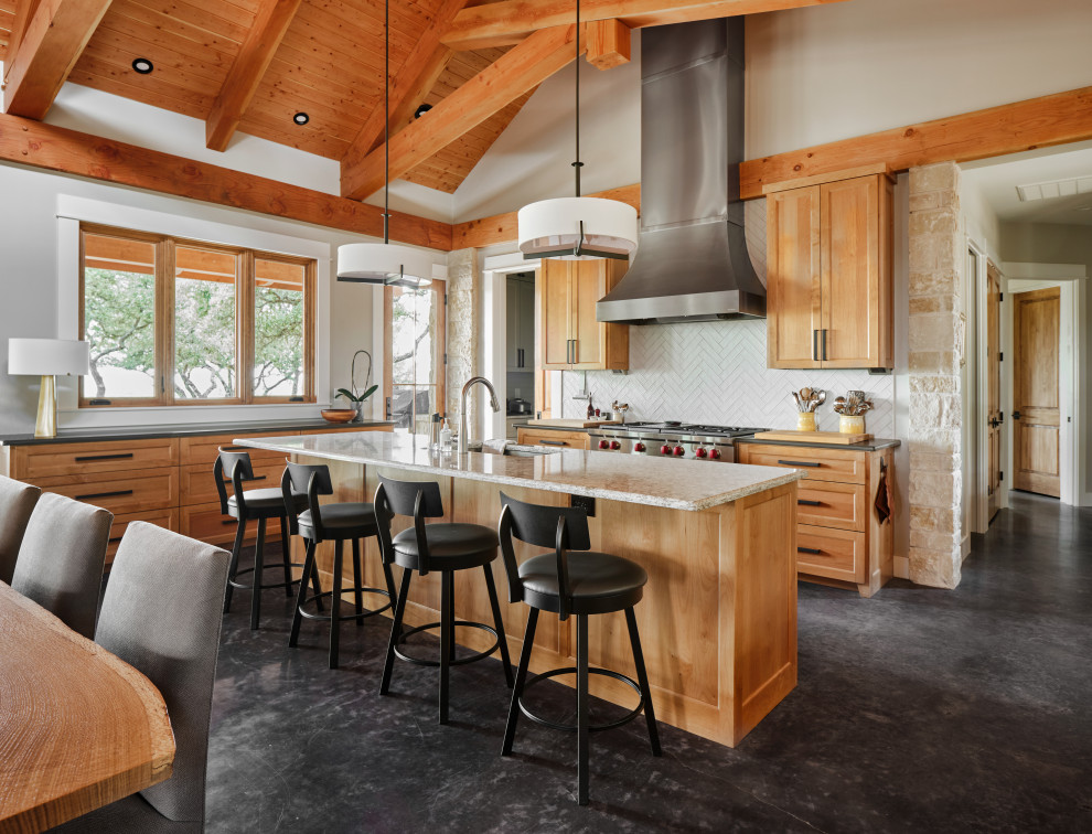 This is an example of a country l-shaped kitchen in Austin with a submerged sink, shaker cabinets, medium wood cabinets, white splashback, stainless steel appliances, concrete flooring, an island, black floors, grey worktops, exposed beams, a vaulted ceiling and a wood ceiling.