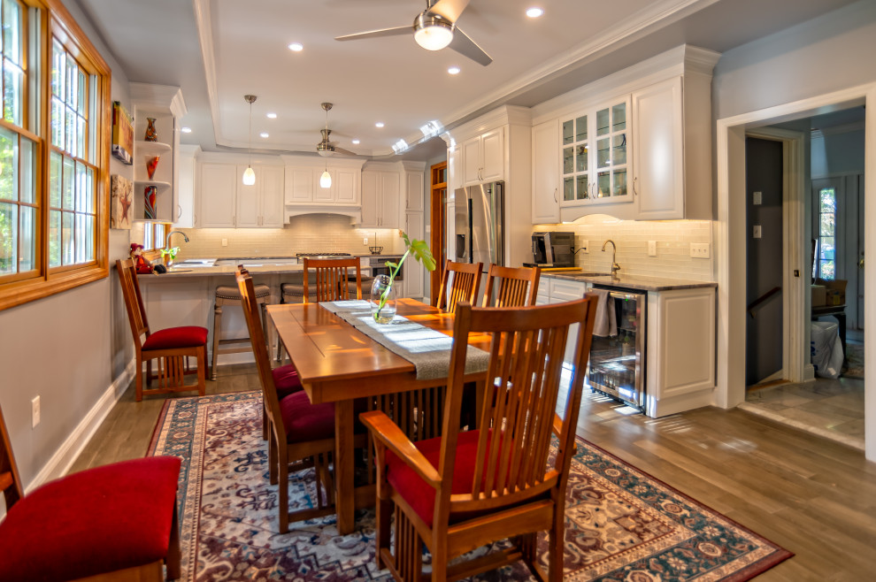 Inspiration for a large timeless u-shaped medium tone wood floor and brown floor eat-in kitchen remodel in Philadelphia with an undermount sink, raised-panel cabinets, white cabinets, granite countertops, yellow backsplash, glass tile backsplash, stainless steel appliances, a peninsula and gray countertops