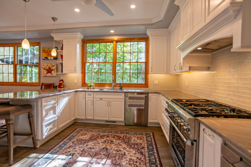 Idéer för ett stort klassiskt grå kök, med en undermonterad diskho, luckor med upphöjd panel, vita skåp, granitbänkskiva, gult stänkskydd, stänkskydd i glaskakel, rostfria vitvaror, mellanmörkt trägolv, en halv köksö och brunt golv