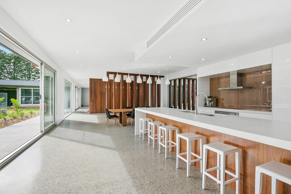 Huge trendy galley concrete floor kitchen photo in Geelong with an undermount sink, flat-panel cabinets, white cabinets, quartz countertops, wood backsplash, stainless steel appliances and an island