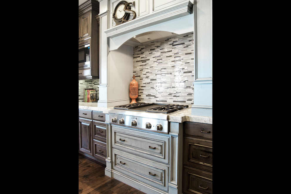 Inspiration for a large timeless galley dark wood floor eat-in kitchen remodel in Salt Lake City with a farmhouse sink, raised-panel cabinets, gray cabinets, granite countertops, multicolored backsplash, matchstick tile backsplash, stainless steel appliances and an island