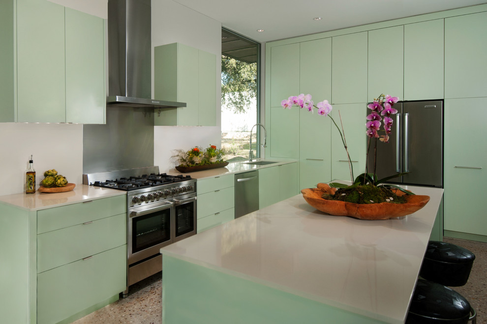 Design ideas for a medium sized midcentury u-shaped enclosed kitchen in Austin with a submerged sink, flat-panel cabinets, green cabinets, engineered stone countertops, white splashback, stainless steel appliances and concrete flooring.