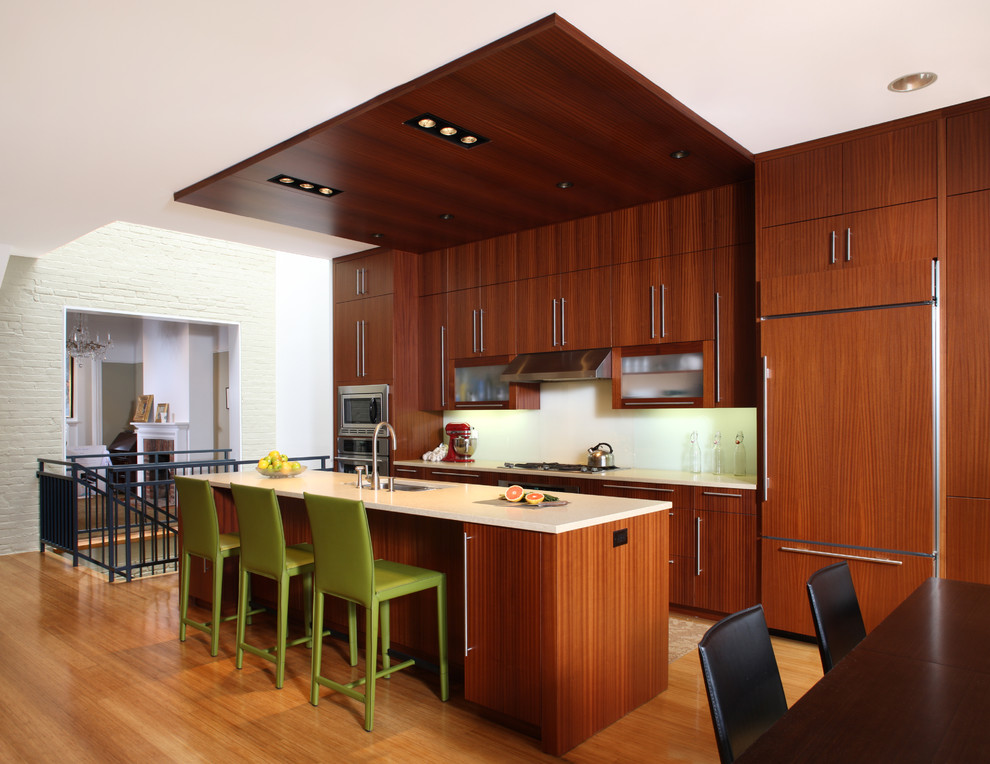 Photo of a contemporary galley kitchen in DC Metro with a submerged sink, flat-panel cabinets, dark wood cabinets, white splashback, integrated appliances, medium hardwood flooring and an island.