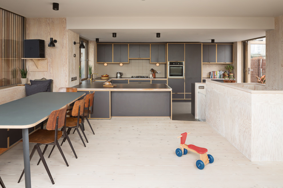 Photo of a medium sized contemporary u-shaped kitchen/diner in London with a submerged sink, flat-panel cabinets, grey cabinets, vinyl flooring and grey floors.