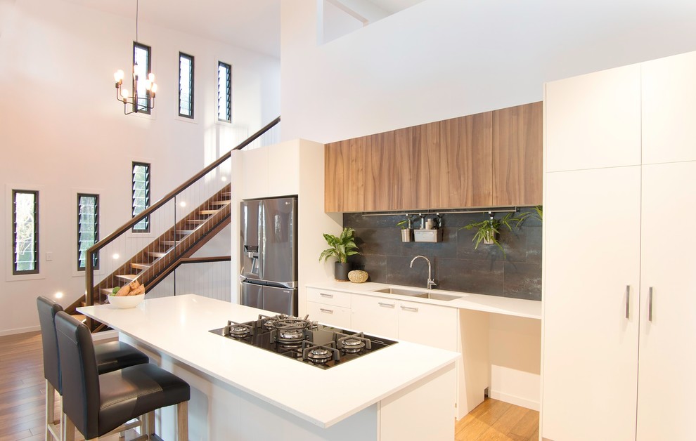 Example of a trendy bamboo floor kitchen design in Other with a double-bowl sink, quartz countertops, metallic backsplash, stainless steel appliances, an island and white countertops