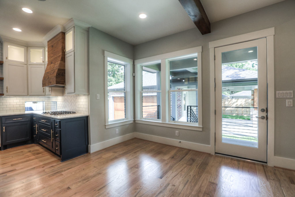 Inspiration for a large midcentury u-shaped open plan kitchen in Houston with a belfast sink, shaker cabinets, black cabinets, granite worktops, white splashback, ceramic splashback, stainless steel appliances, medium hardwood flooring, an island and brown floors.