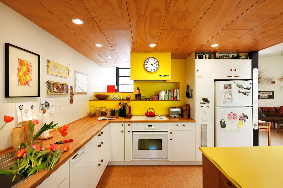 Modelo de cocinas en L bohemia con fregadero encastrado, armarios con paneles lisos, puertas de armario blancas, salpicadero amarillo, electrodomésticos blancos, una isla y encimeras amarillas