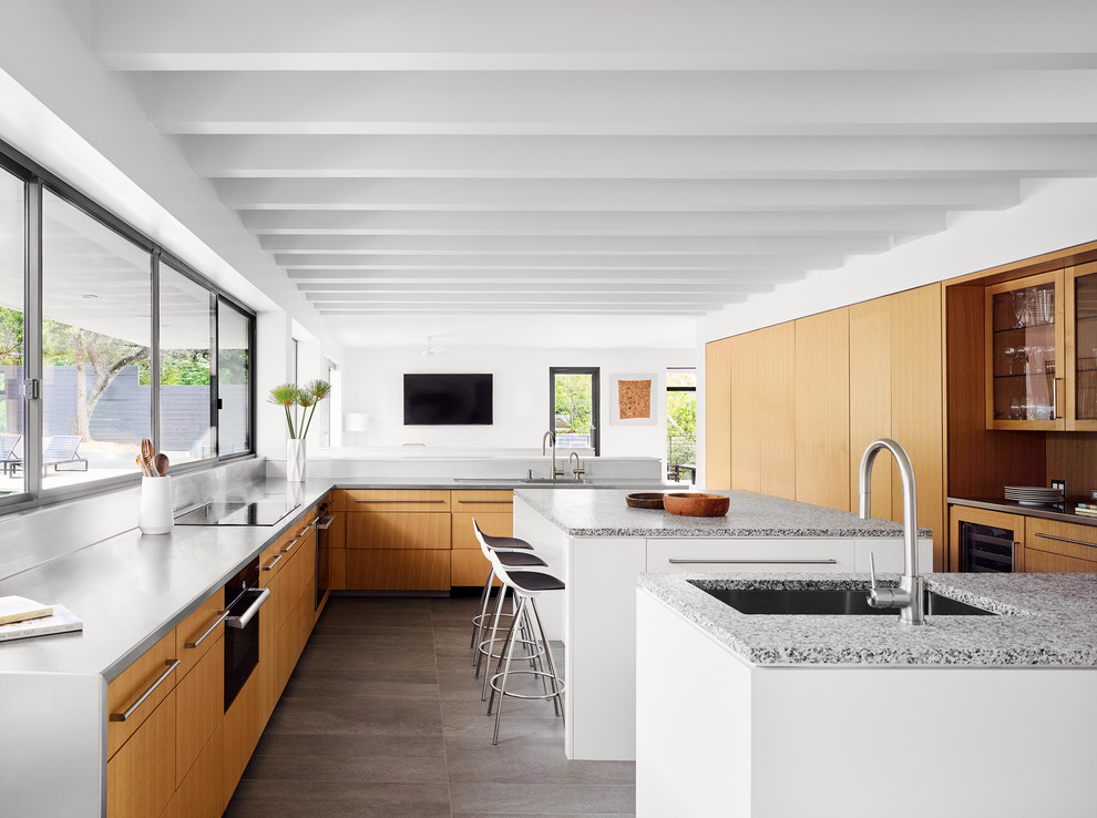 Bild på ett funkis grå grått kök, med en undermonterad diskho, släta luckor, skåp i mellenmörkt trä, fönster som stänkskydd, integrerade vitvaror, flera köksöar och grått golv