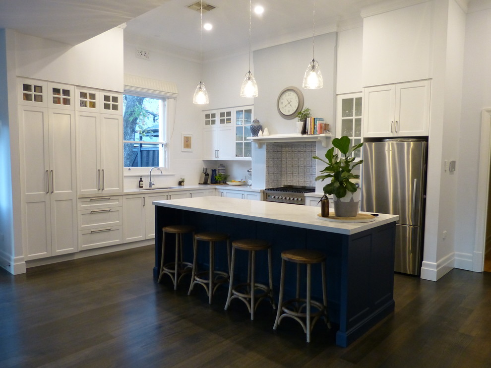 Exempel på ett stort klassiskt kök, med en undermonterad diskho, skåp i shakerstil, vita skåp, bänkskiva i kvarts, vitt stänkskydd, stänkskydd i keramik, rostfria vitvaror, mellanmörkt trägolv, en köksö och brunt golv