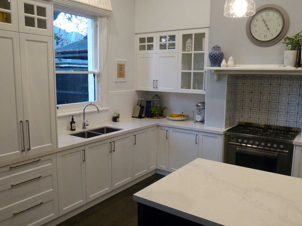Exempel på ett stort klassiskt kök, med en undermonterad diskho, vita skåp, bänkskiva i kvarts, vitt stänkskydd, stänkskydd i keramik, rostfria vitvaror, mellanmörkt trägolv, en köksö och brunt golv