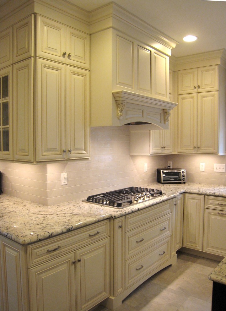 Large elegant l-shaped porcelain tile and beige floor eat-in kitchen photo in Bridgeport with an undermount sink, raised-panel cabinets, white cabinets, granite countertops, beige backsplash, stainless steel appliances, an island and multicolored countertops