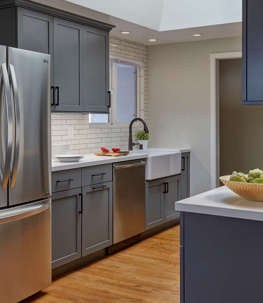Inspiration for a mid-sized transitional galley eat-in kitchen remodel in San Francisco with a farmhouse sink, shaker cabinets, gray cabinets, quartzite countertops, white backsplash, subway tile backsplash, stainless steel appliances, an island and white countertops