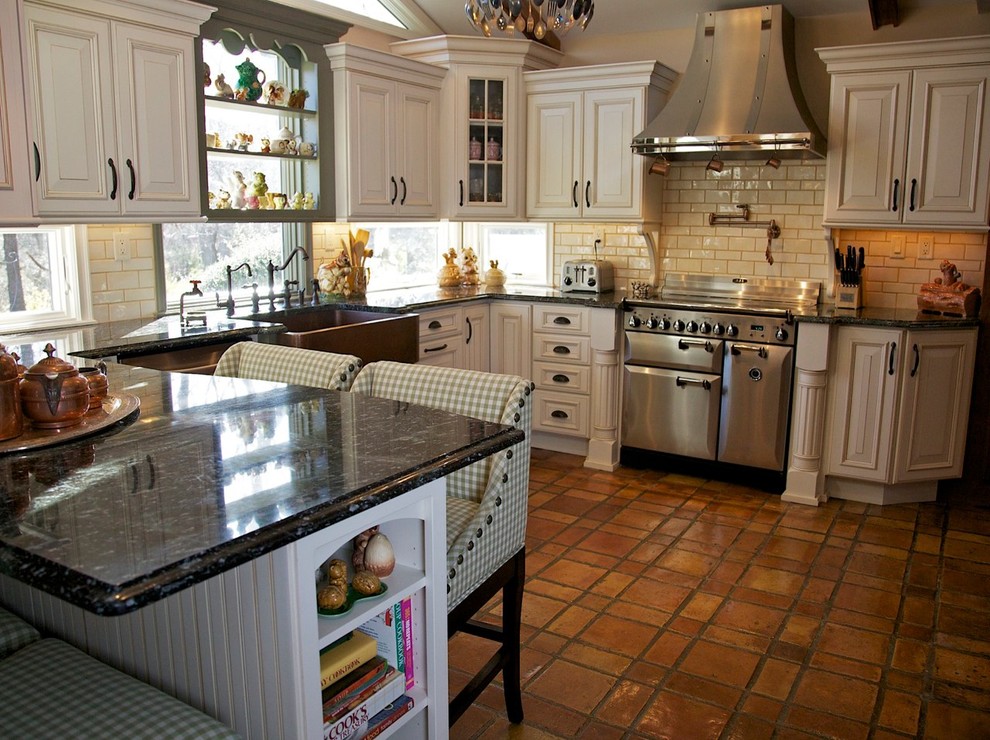 Inredning av ett rustikt avskilt, stort u-kök, med en rustik diskho, luckor med upphöjd panel, beige skåp, marmorbänkskiva, rostfria vitvaror och klinkergolv i terrakotta
