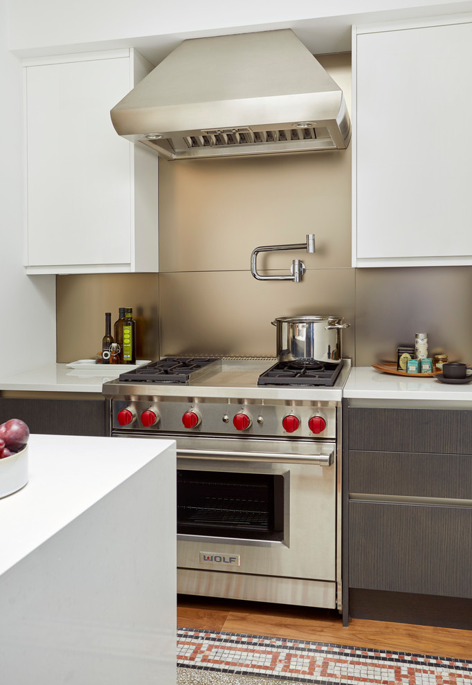 Bild på ett mellanstort funkis vit vitt kök, med en undermonterad diskho, släta luckor, stänkskydd med metallisk yta, glaspanel som stänkskydd, rostfria vitvaror, mellanmörkt trägolv, en köksö, vita skåp och bänkskiva i kvartsit